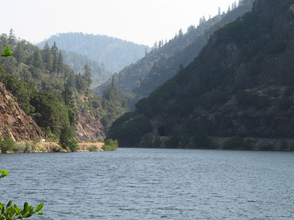 Looking back up the river, with the road on the left and the railway emerging from the tunnel on the right